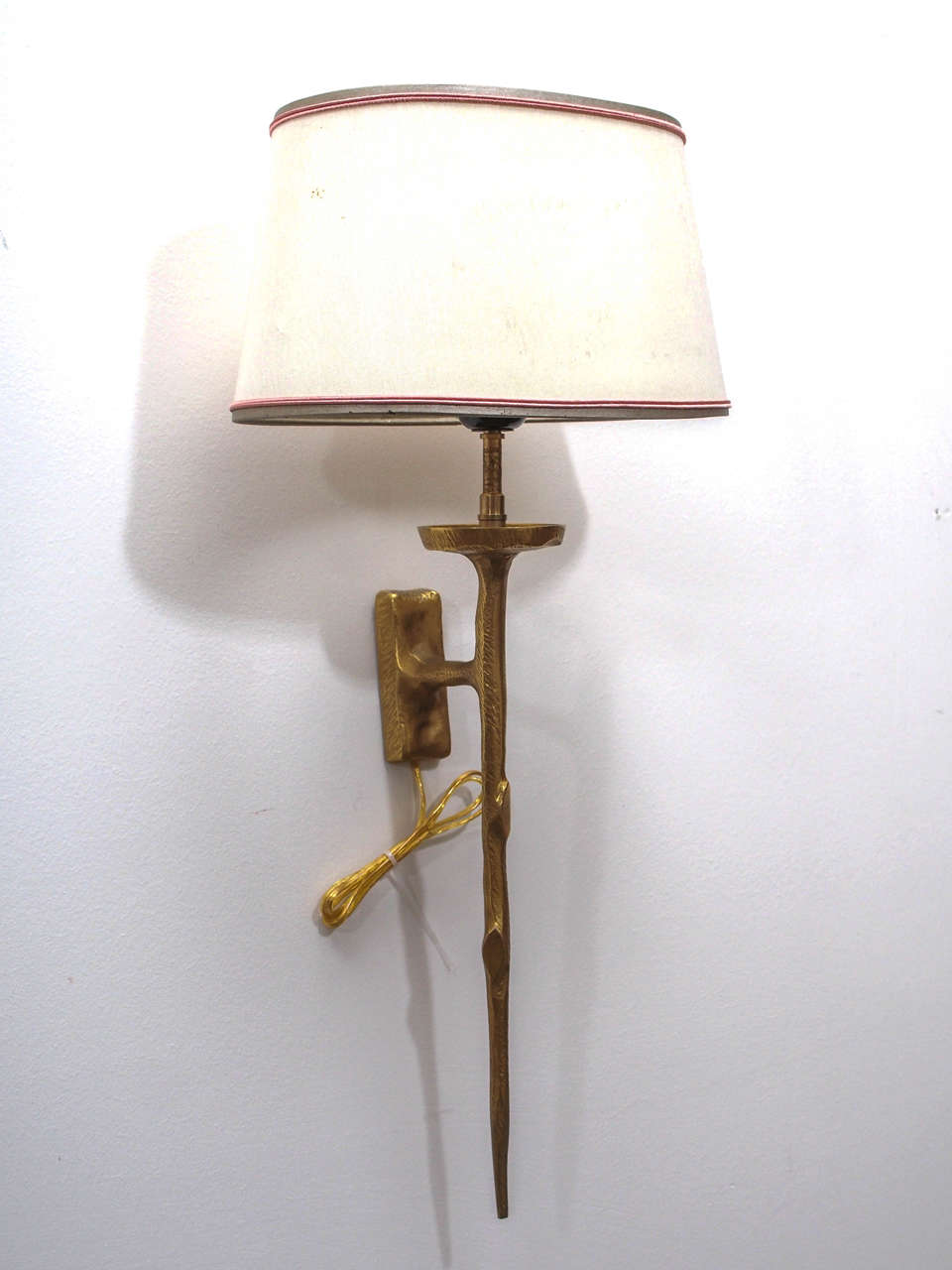 Single sconce in gilt bronze of stylized twig form; the oval linen shade attractively banded.
